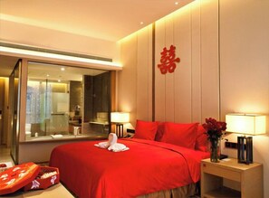 A hotel room with a large bed, a mirror, a bedside table with a lamp, and a red wall decoration. - Days Hotel by Wyndham Chongqing Liangping (Chongqing)