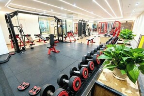 Ein Fitnessstudio mit Gewichthebern, Bänken und einer Spiegelwand.