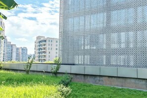 Ein modernes Gebäude mit Metallfassade, umgeben von Grünflächen und anderen Wohnhäusern.