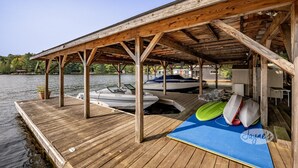 Un muelle de madera con un área cubierta, barcos y una tabla de remo.