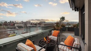 Une terrasse sur le toit avec des sièges extérieurs, un foyer et une vue sur le paysage urbain et la rivière.
