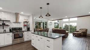 A modern kitchen with white cabinetry, a central island, stainless steel appliances, and pendant lighting. - Pocono Mountains Camelback Retreat Ski-in Ski-out (Tannersville)