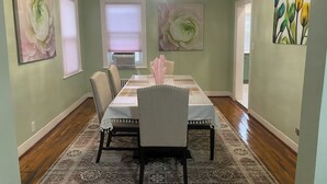 A dining room with a rectangular table, six chairs, and a chandelier. - Charming 3-bedroom house in Queens with WiFi and AC (Queens)