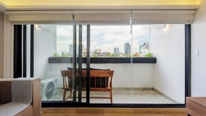 Un saló modern amb una porta corredissa de vidre que dona a un balcó amb vista a la ciutat.