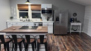 Una cocina moderna con una isla central, electrodomésticos de acero inoxidable y una zona de comedor con cuatro sillas.