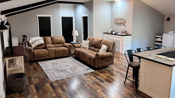 Una sala acogedora con un sofá de cuero marrón, un tapiz estampado y piso de madera.