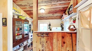 Une cuisine rustique avec des poutres en bois, un buffet en bois doté de portes en verre et un réfrigérateur blanc.