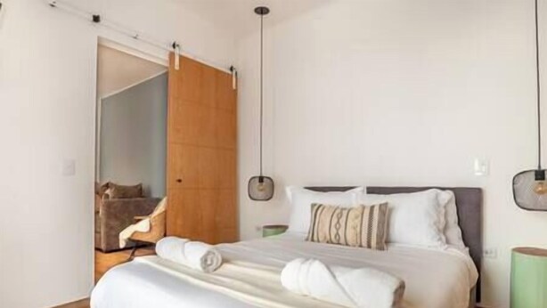 Een slaapkamer met een bed, een houten garderobe en een hanglamp.
