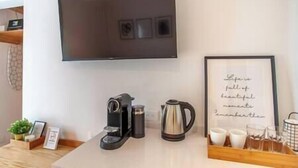 Una cocina moderna con cafetera, hervidor y una cita enmarcada en la pared.