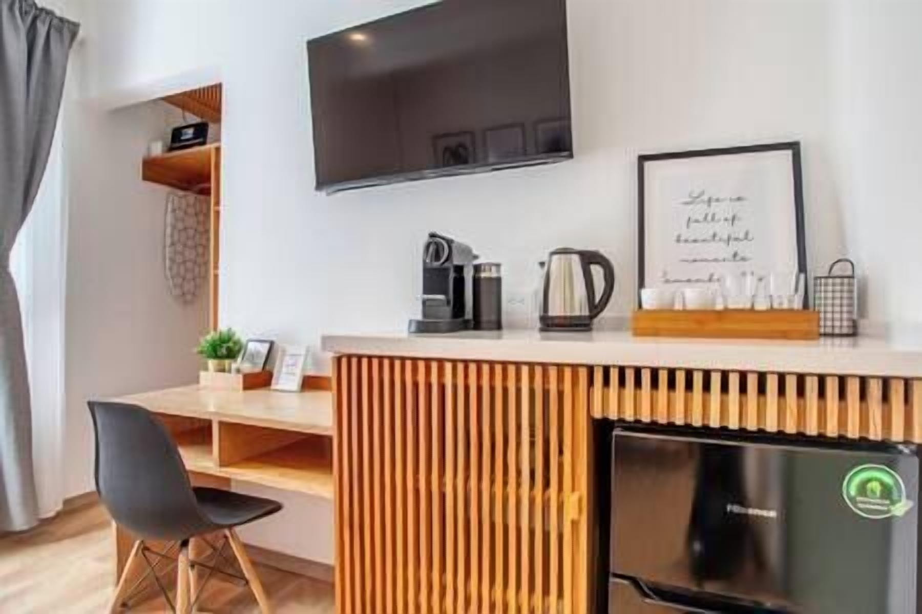 A compact kitchenette with a coffee maker, kettle, and a refrigerator.