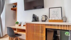 Una kitchenette compacta con cafetera, hervidor y refrigerador.