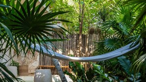 A hammock in a lush garden with a stone wall and potted plants. - Apartment with Private Pool and Garden | •TEVA 1A (Tulum)