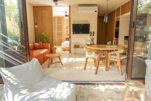 Un intérieur moderne avec une porte vitrée donnant sur un espace repas, un canapé et un lit.