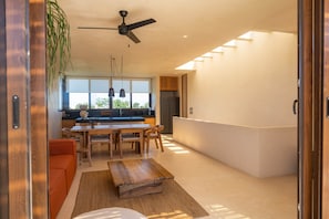A modern kitchen with a dining area, a ceiling fan, and a large window.