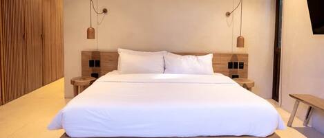 A modern hotel room with a large bed, wooden headboard, and two bedside tables with lamps.