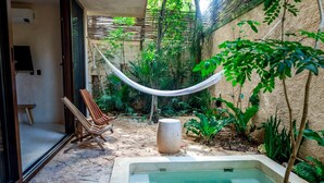 Ein privater Außenbereich mit Pflasterterrasse, kleinem Pool, Hängematte und Sitzgruppe mit Stühlen.