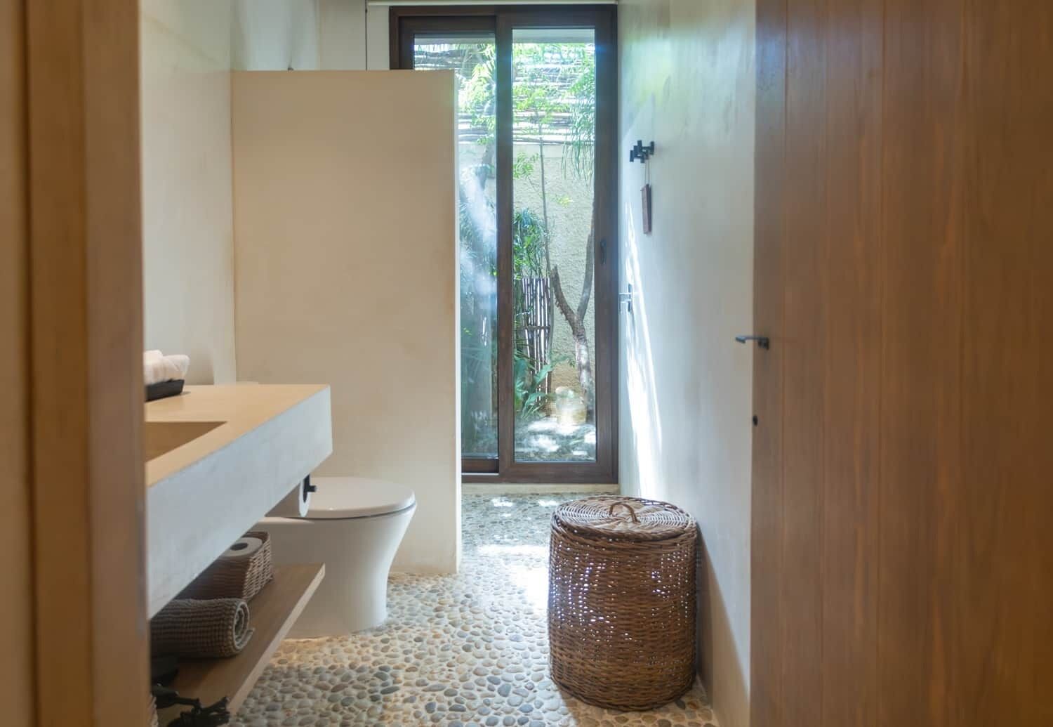 Une salle de bain avec des toilettes, un lavabo et un panier en osier.