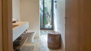 Ein Badezimmer mit Toilette, Waschbecken und einem Korbwannenaufsatz.