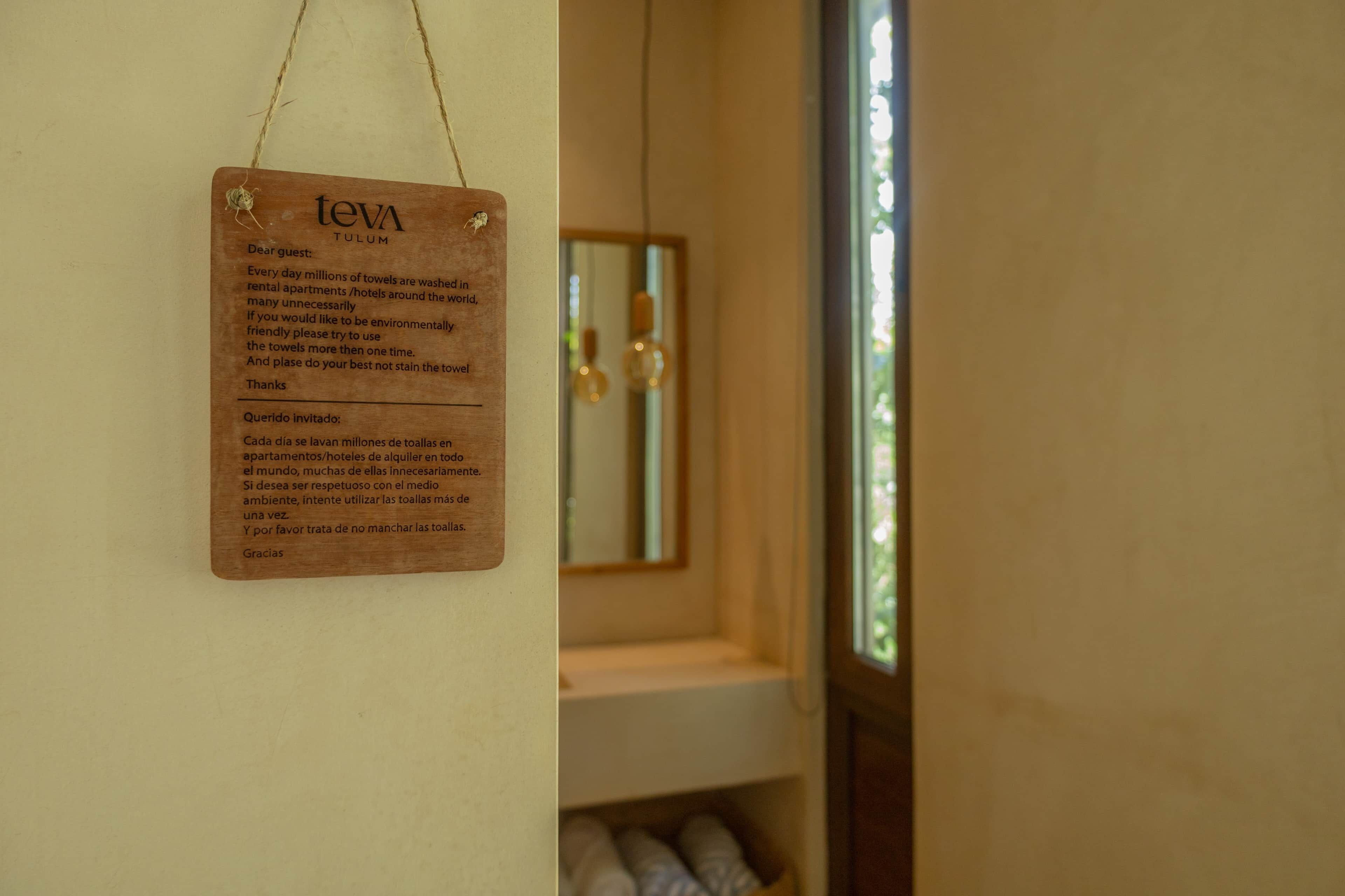 A wooden sign with text in English and Spanish, hanging on a wall.