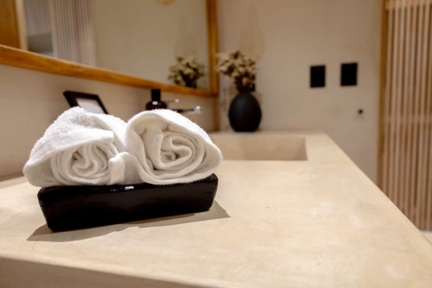 Een netjes opgevouwen handdoek op een zwart dienblad op een beige aanrecht in een hotelkamer.