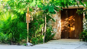 Un edificio de piedra con una puerta de madera, rodeado de abundante follaje verde.