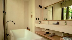 Un baño moderno con una bañera grande, un tocador con espejo y una zona de ducha.