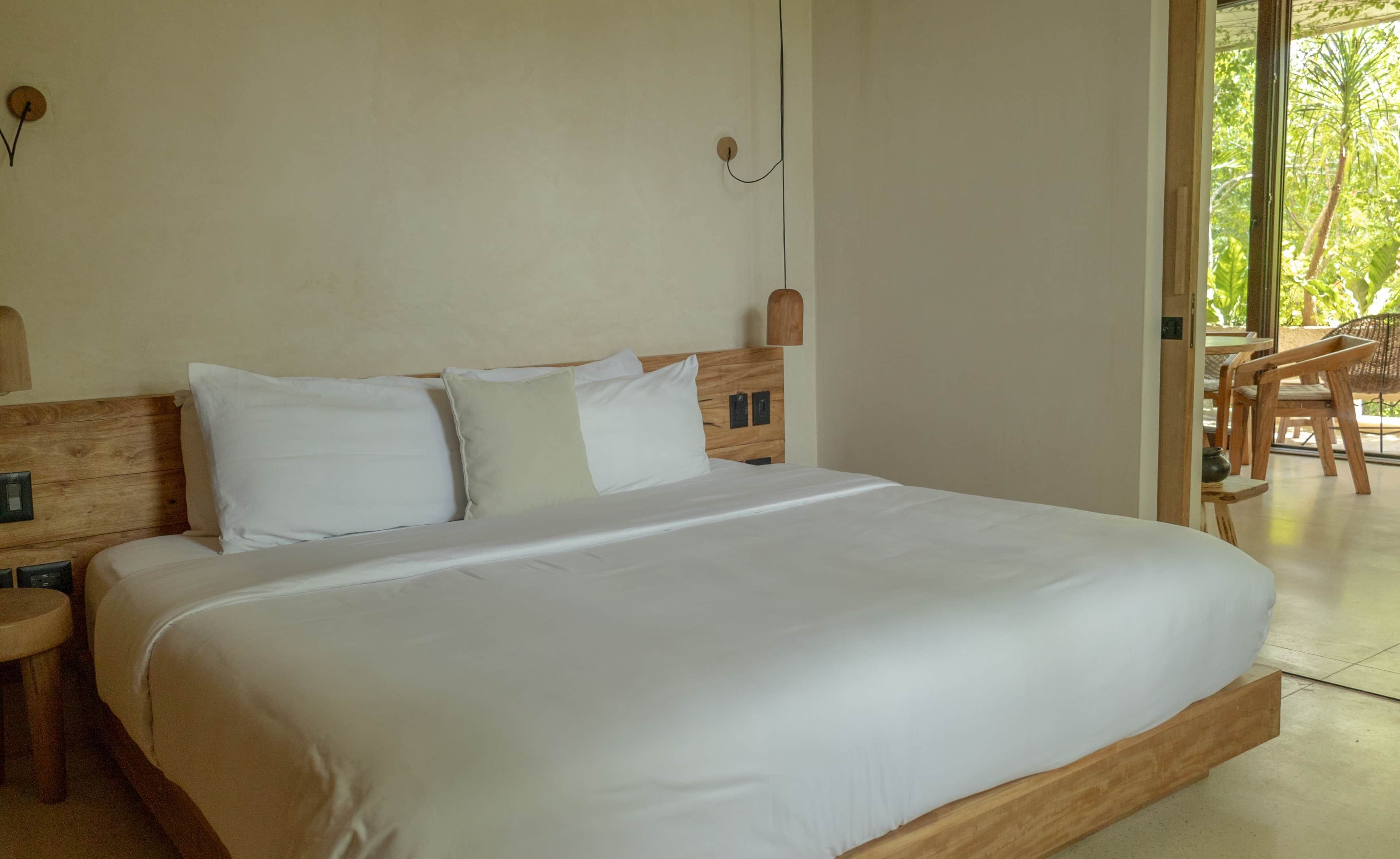 A large bed with white linens, a wooden headboard, and two bedside tables.