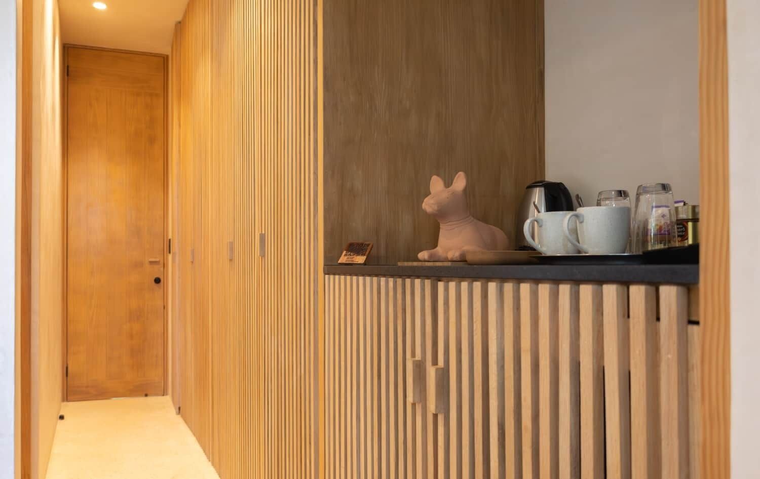 Una cocina moderna con diseño de paneles de madera, una figurita de conejo de cerámica y una cafetera sobre la encimera.