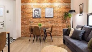A living room with a brick wall, a round dining table with chairs, a sofa, and a floor lamp. - Alvaro · Great location. Renovated apartament in Roma Norte (Mexico City)