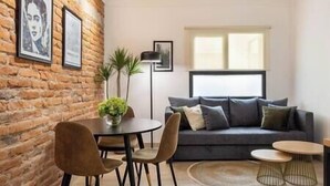 A living room with a brick wall, a grey sofa, a round table, and a floor lamp. - Alvaro · Great location. Renovated apartament in Roma Norte (Mexico City)
