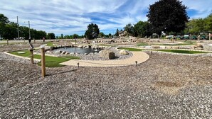 Ein angelegter Garten mit einem zentralen Teich, Wegen und üppiger Bepflanzung.