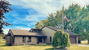 Ein zweistöckiges Haus mit Veranda, Fahnenmast mit amerikanischer Flagge und gepflegtem Rasen.