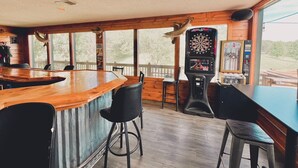 Eine Bar mit Holzbalken, schwarzen Barhocker und Dartscheibe.