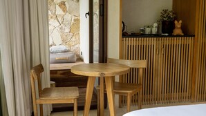 A wooden table with chairs in a room with a stone wall and a wooden slat partition. - Room with Private Terrace and Pool |• TEVA 3B (Tulum)