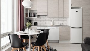 A modern kitchen with white cabinetry, a built-in microwave, and a white refrigerator. - Borg Housing Travel Center (Pori)