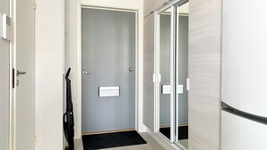A modern hallway with a closed door, a black mat at the entrance, and a sliding glass door leading to another room. - Borg Housing Travel Center (Pori)