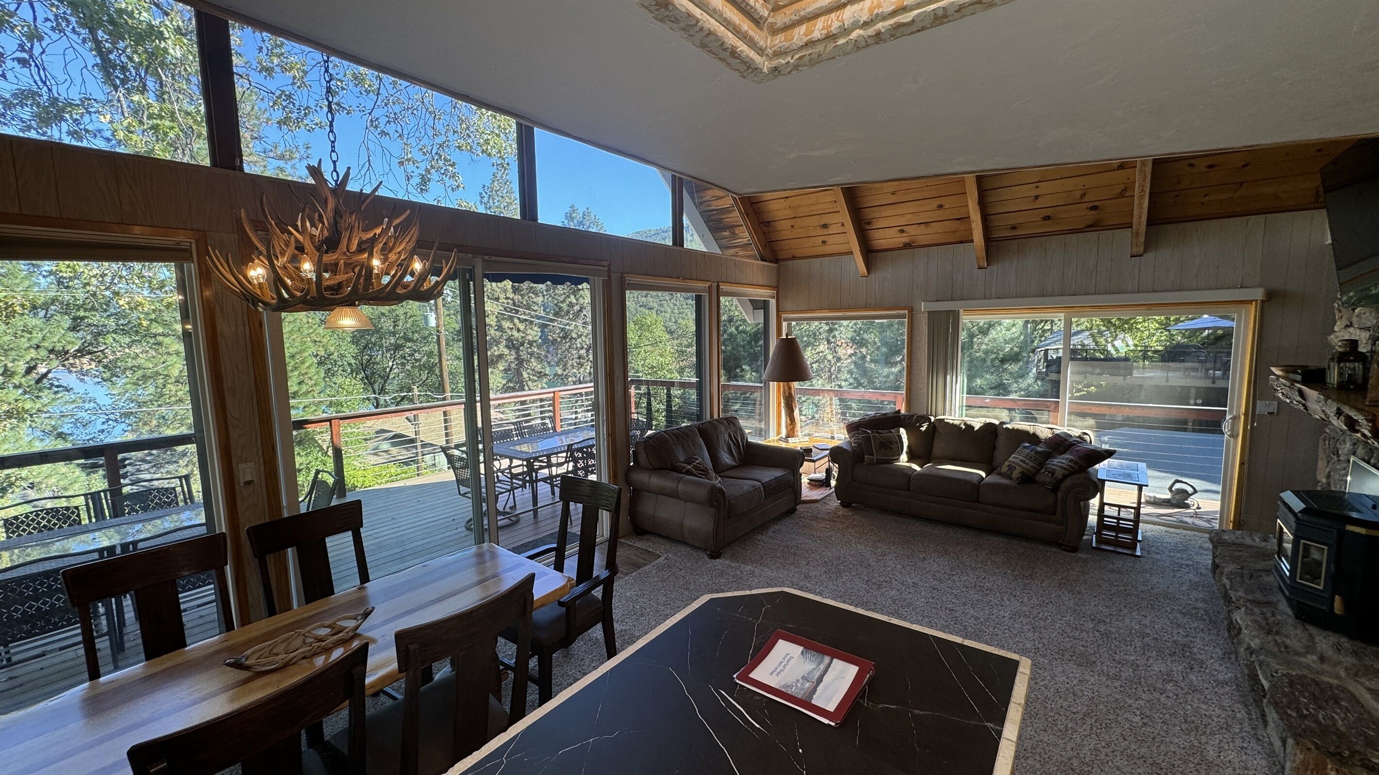 A spacious living room with large windows, a wooden ceiling, and a cozy seating area.