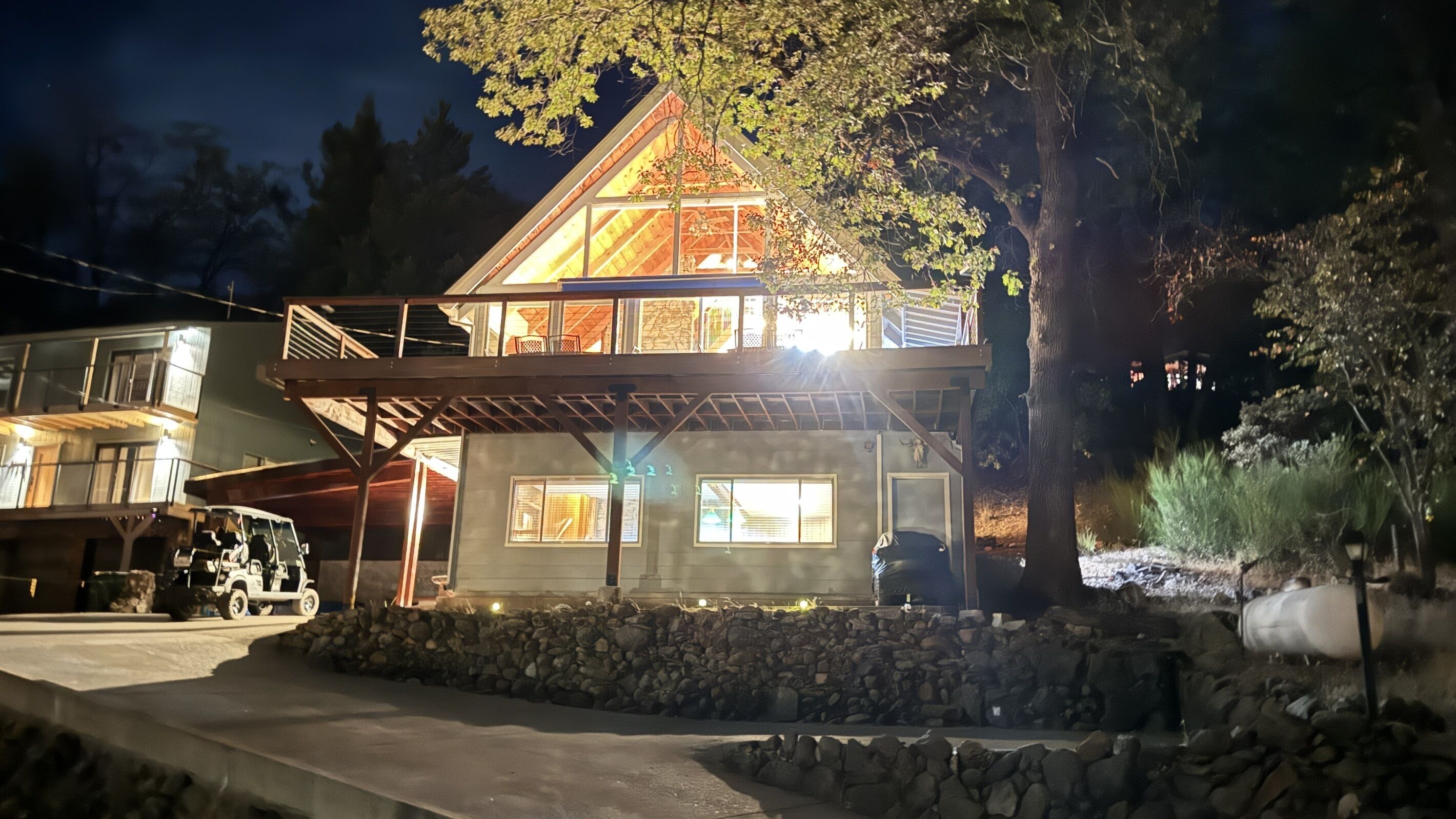 Una casa a due piani con un balcone, fondamenta in pietra e un vialetto.
