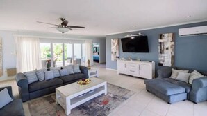 Ein modernes Wohnzimmer mit grauem Sofa, weißem Couchtisch und Deckenventilator.
