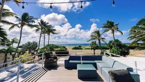 Eine Terrasse mit Sitzgelegenheiten im Freien und Blick auf Strand und Meer.