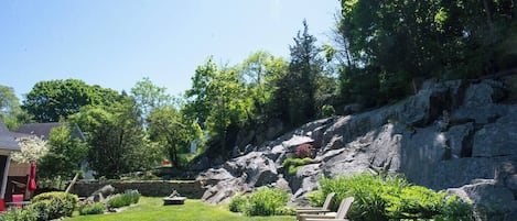 Un jardin avec une pelouse, une chaise en bois et un mur de pierres.