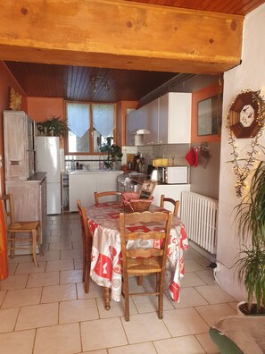 A cozy kitchen with a dining table, chairs, and a refrigerator. - Country house 4 minutes from La Bourboule. (La Bourboule)