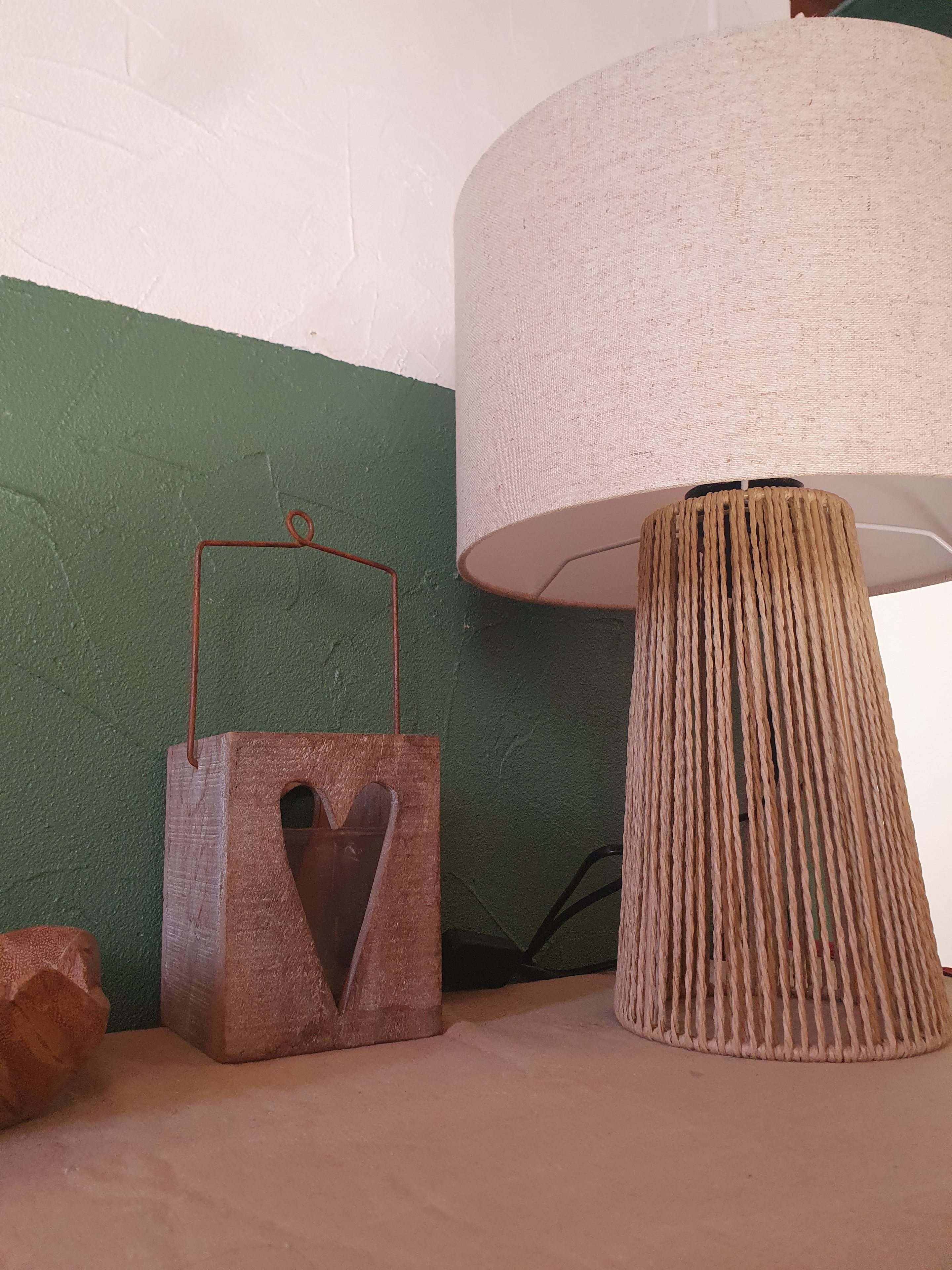 Una lámpara con pantalla texturizada y base de madera con un corte en forma de corazón.