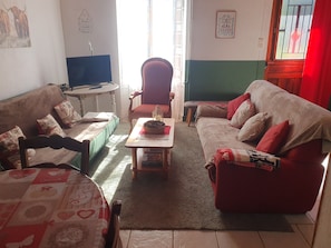 Una sala de estar con un sofá, un sillón y una mesita con una cesta.