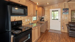 A kitchen with wooden cabinets, a black stove, a microwave, and a coffee maker. - Sun Outdoors Lake Rudolph (Santa Claus)