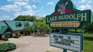 Un panneau d’indication pour le camping situé au bord du lac Rudolph, avec un message de bienvenue adressé aux personnes qui aiment prendre le soleil.