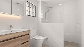 A modern bathroom with a glass-enclosed shower, a white sink, and a wooden vanity. - HuskySun by Experience Jervis Bay (Huskisson)