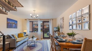 Una sala de estar moderna con sofá, mesa de centro y mesa de comedor preparada para seis personas.