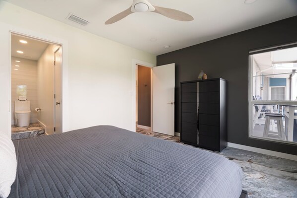 A bedroom with a bed, a wardrobe, a ceiling fan, and a view through a window.