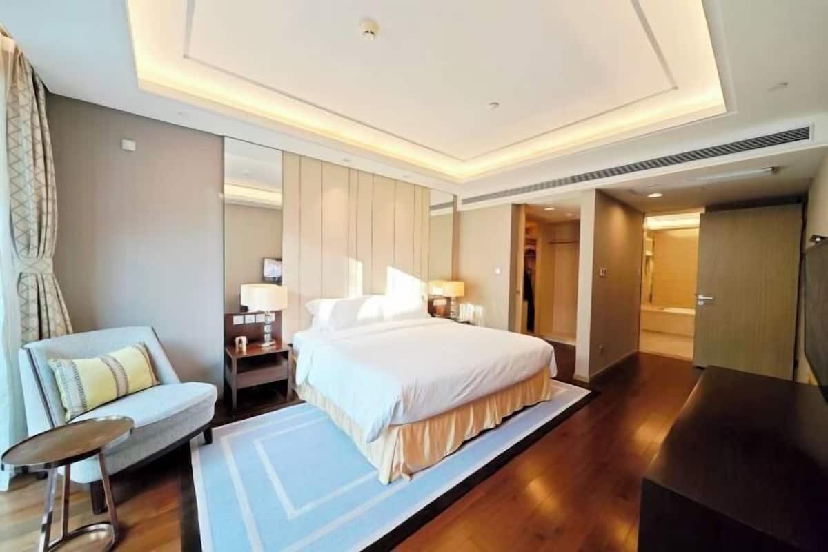 A modern hotel room with a large bed, a sofa, a small table, and a mirror.